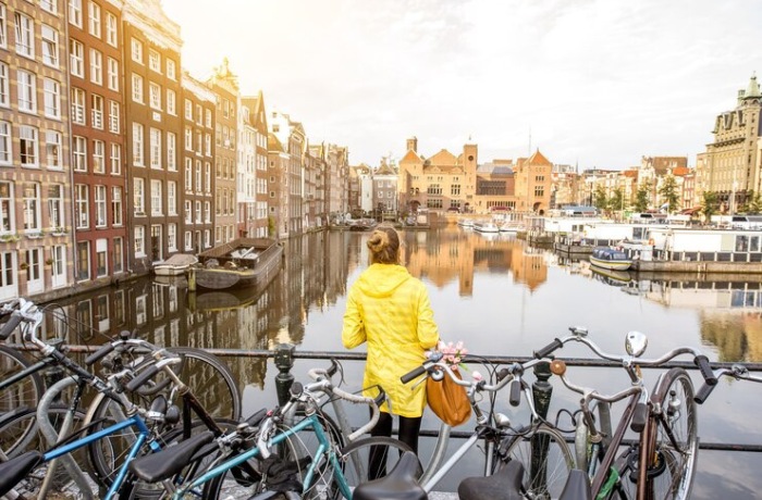 Young woman in yellow raincoat enjoying morning view on the beautiful cityscape view in Amsterdam